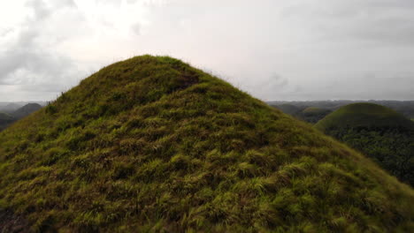 close flyover reveal view of bohol's chocolate hills with dramatic sky, philippines