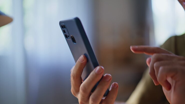 Freelancer tippt mit dem Finger auf den Bildschirm eines Mobiltelefons, um einen Video-Chat von zu Hause aus zu starten (Nahaufnahme)