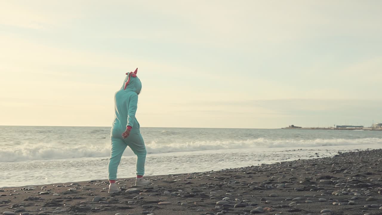 해가 지면 해변에서 는 유니콘 잠옷을 입은 소녀