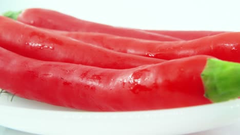 a rotating plate with spicy red chili peppers, macro shot, 4k, white background, slow motion