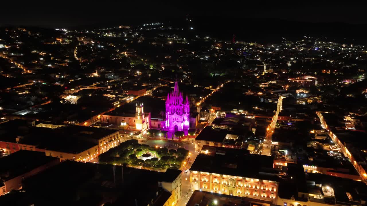 hiperlapse orbital olhando sobre a paróquia de san miguel arcángel iluminado em roxo à noite