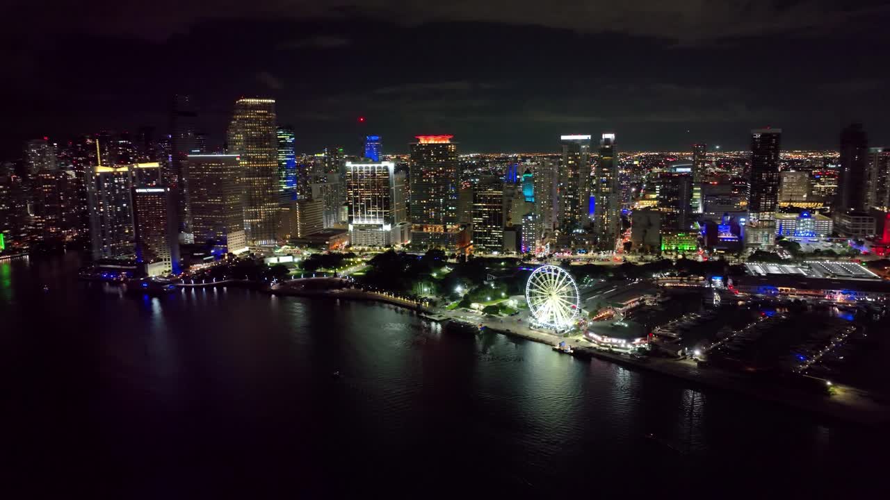 Aerial view of Sky views Miami Observation Wheel at Bayside Marketplace with high illuminated skyscrapers of Brickell, city's financial center