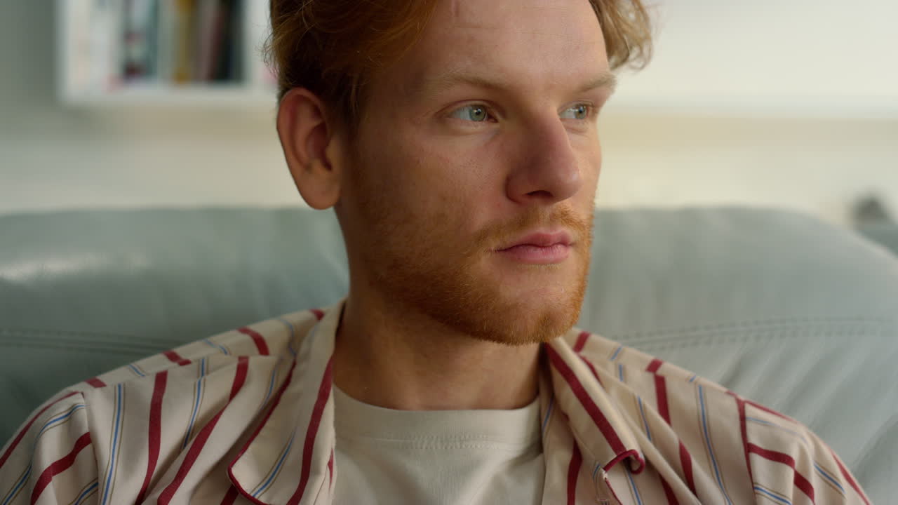 hombre sereno relajándose en casa en pijama de cerca. hombre rojo satisfecho disfrutando del fin de semana