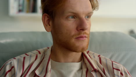 serene guy relaxing home in pajamas closeup. satisfied ginger man enjoy weekend