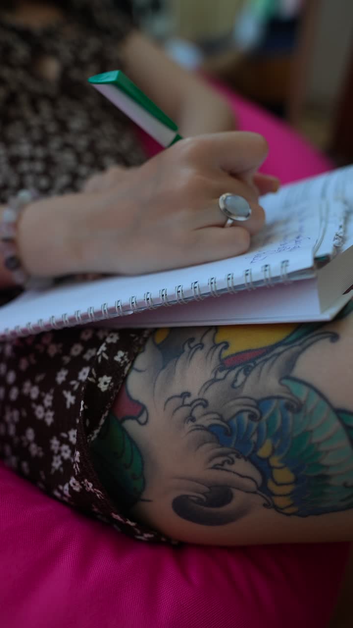 mujer escribiendo en un cuaderno con un tatuaje en la pierna