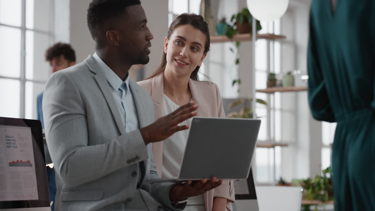 african american team leader man brainstorming with business woman colleague using laptop computer showing ideas pointing at screen working together in office
