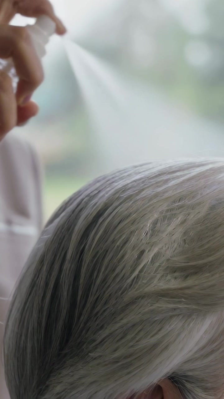 縦型動画：自宅で身だしなみを整えるため、介助者の手がポンプを押し、高齢者の白髪にミストをかける