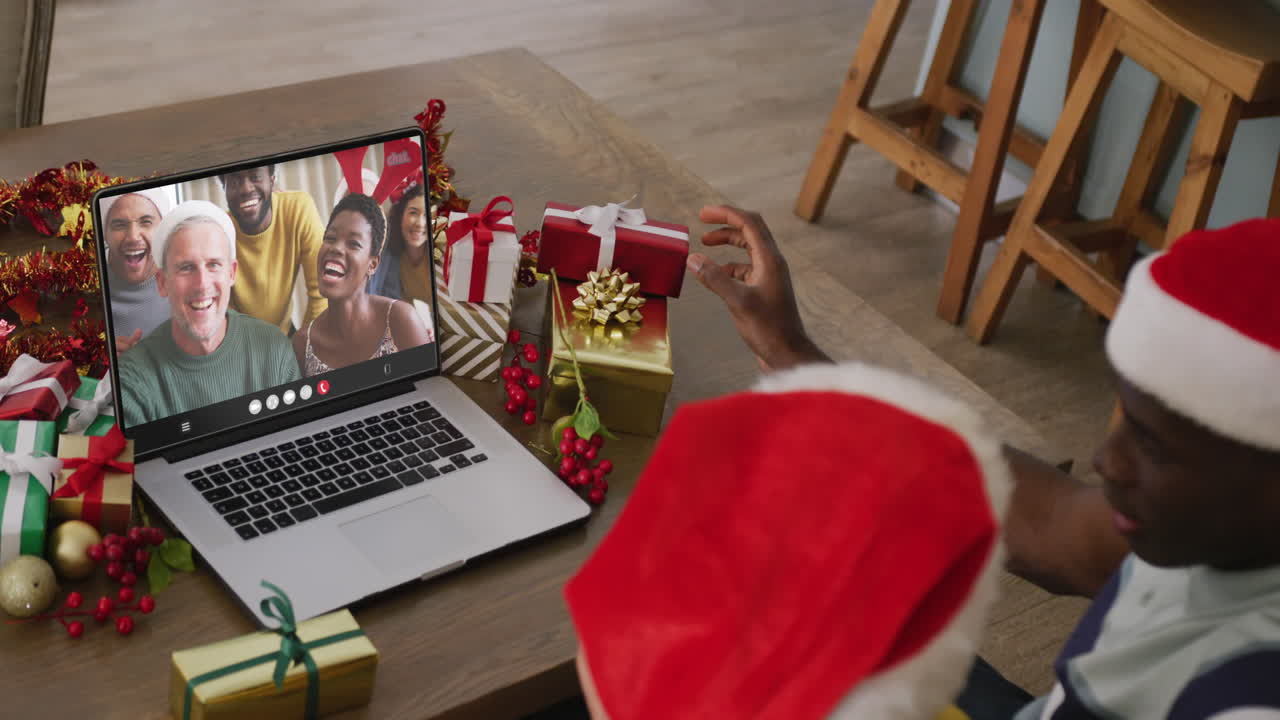 pareja diversa con sombreros de santa teniendo llamada de video portátil con amigos diversos felices