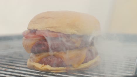 making american fat smash burger with fresh tomatoes and cheese on grill close-up macro. beef or pork cutlet smashing by burger press. the chef in kitchen of the restaurant making cutlets for burgers - smash burger beefsteak. fast and street food concept.
