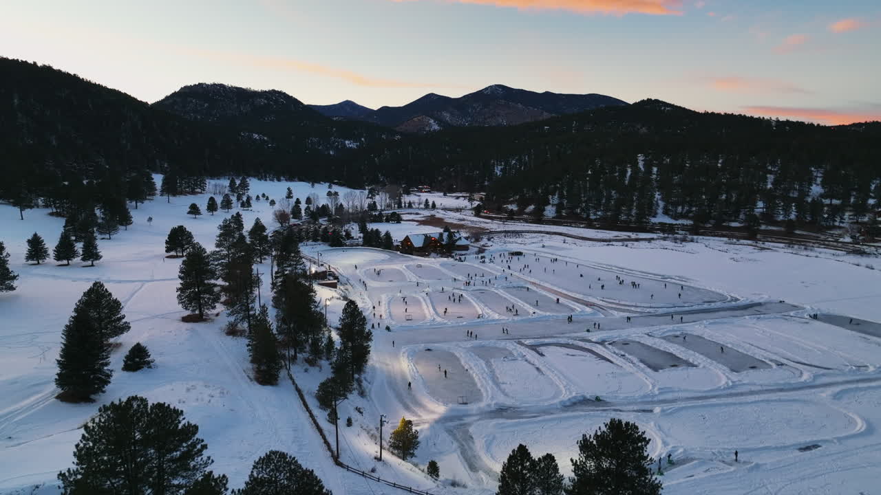 Mid winter Colorado Evergreen Lake under lights sunset playing hockey and ice skating at various rinks pan left