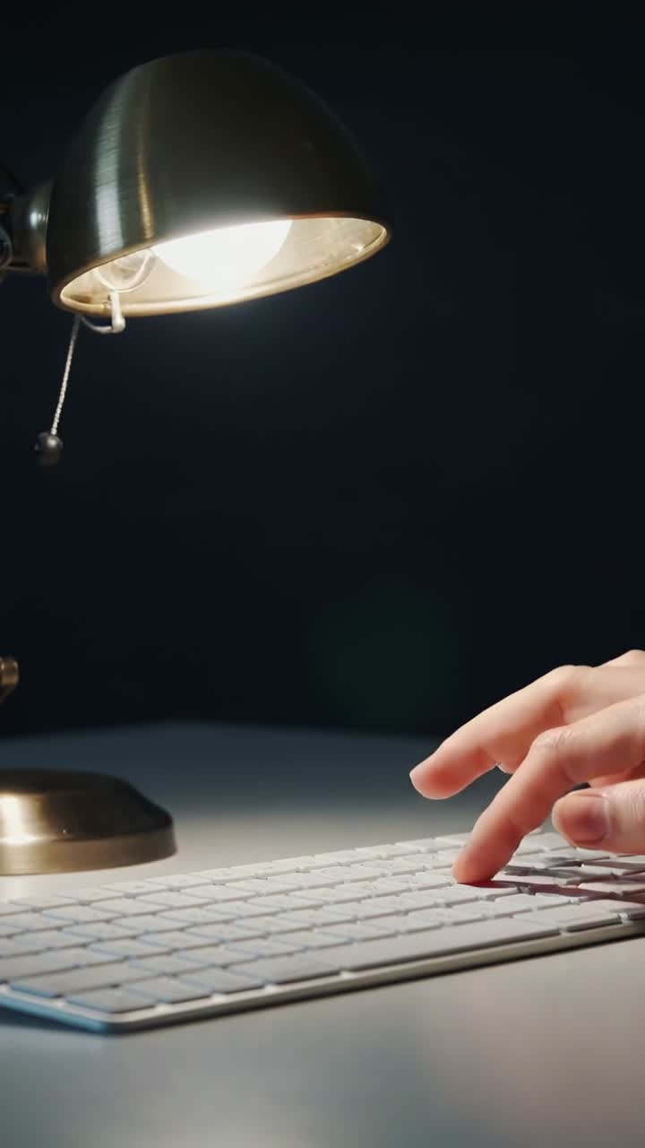 Vertical video: Entering right hand tapping lamp chain at desk to see keys, typing keys, copy space