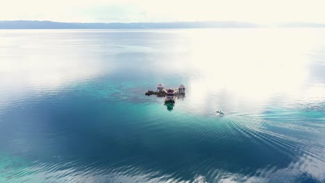 Distant-View-Of-A-Boat-Approaching-The-Water-Cottage-At-Tagbak-Marine-Park-In-Southern-Leyte,-Philippines