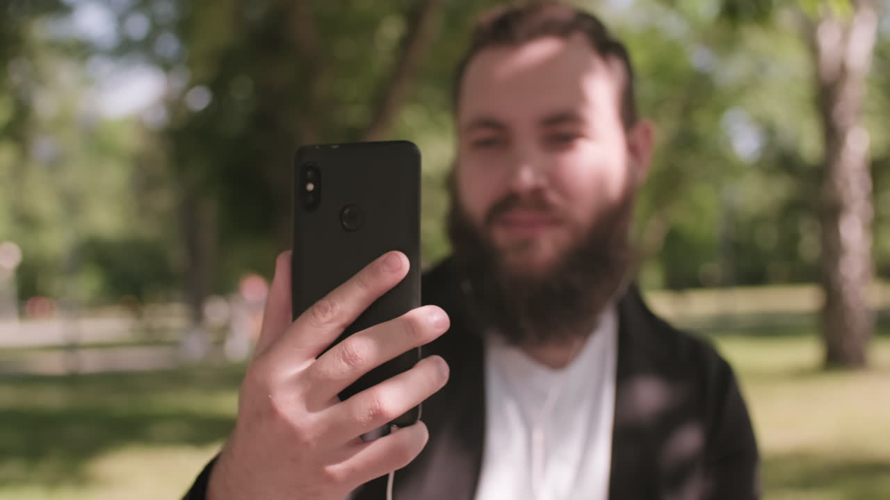 Bearded Man Video Calling on Mobile Phone Outdoors
