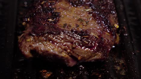 closeup tilt down, juicy marinated beef steak grills on cast iron griddle