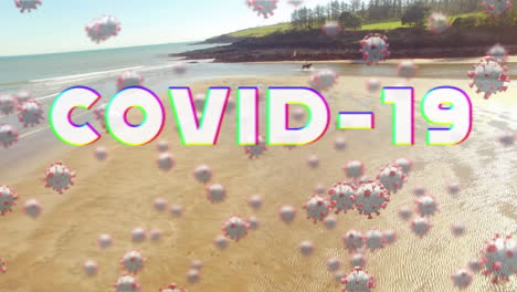 digital composite video of covid-19 text and cells moving against beach in background