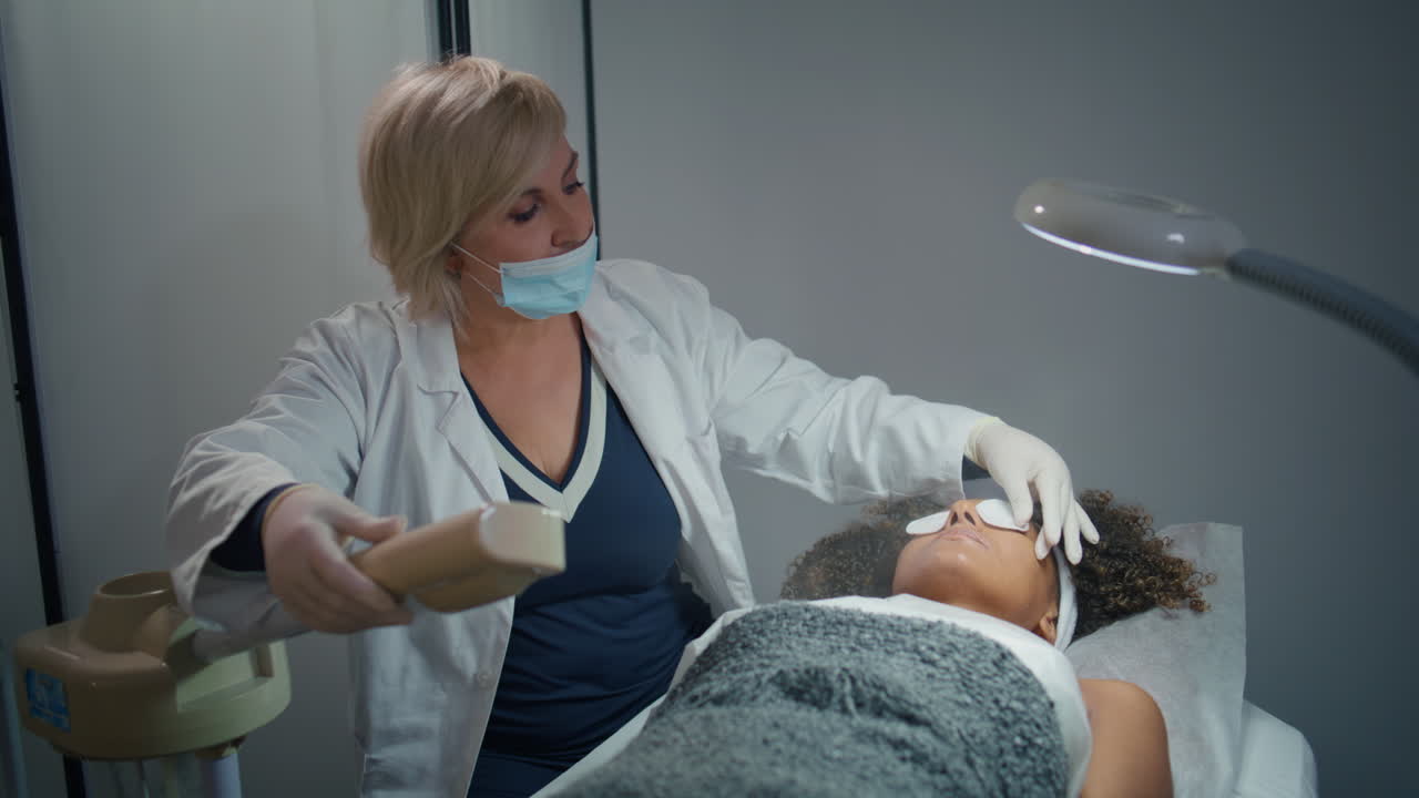 cosmetician haciendo tratamiento de la piel en un salón de belleza. persona acostada en el sofá