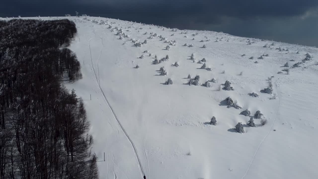Aerial pan of snowy forest and mountaineers near Chumerna peak, Bulgaria
