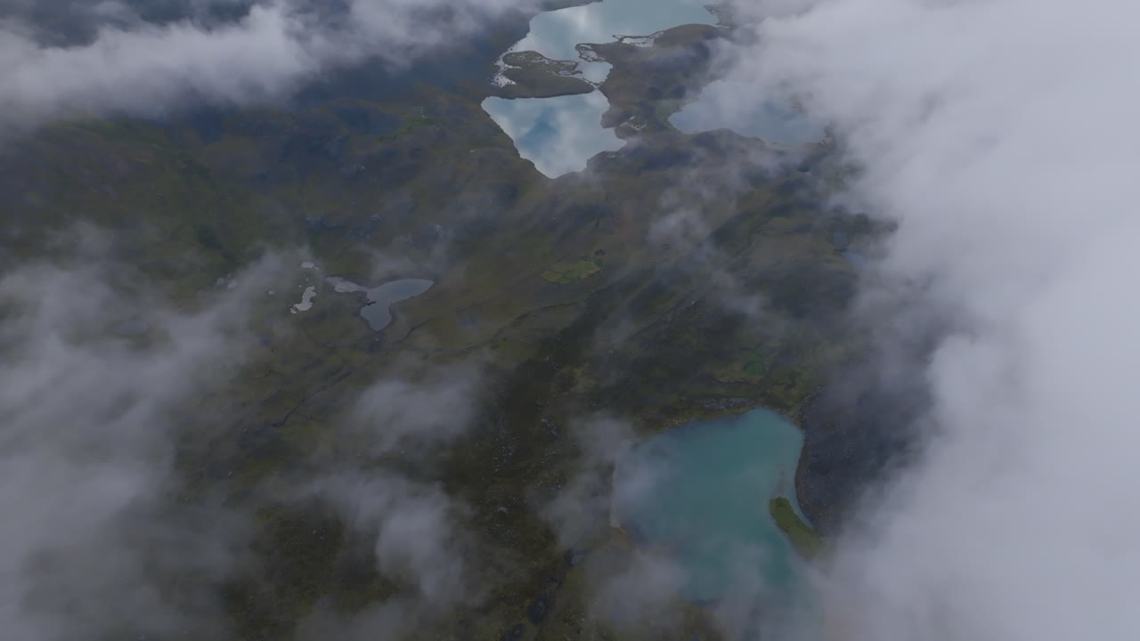 Aerial footage flying above the clouds in Peru with aquamarine lakes in view in Ausangate