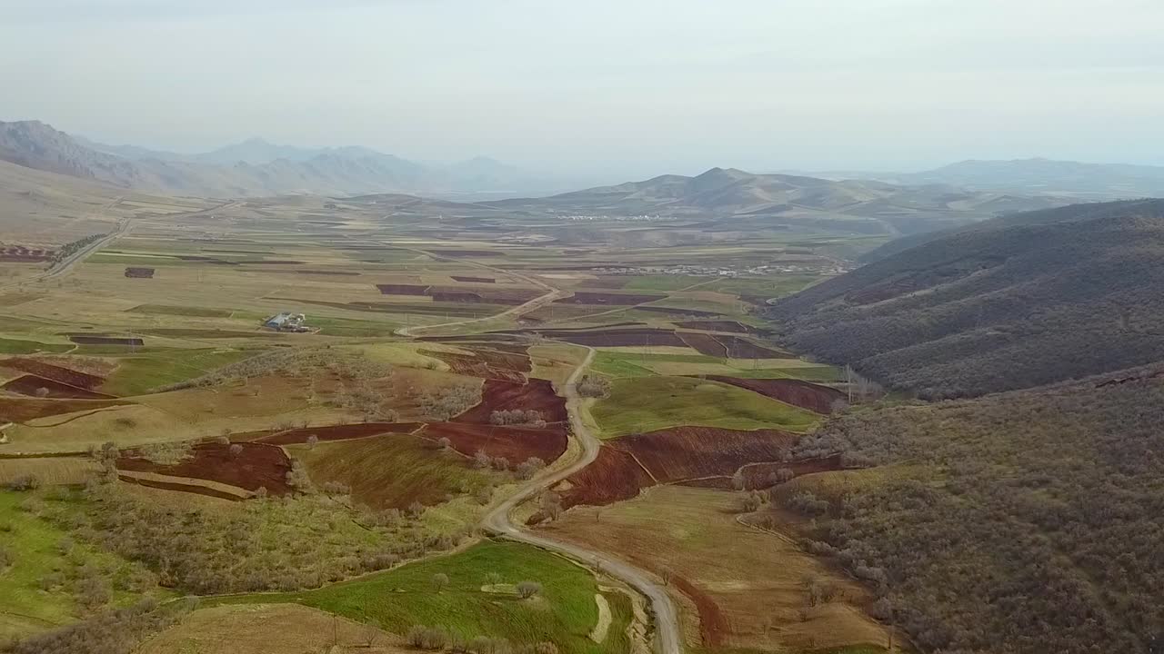 Bellissimo campo verde con paesaggio cinematografico, fattoria e campi ai piedi delle montagne con alcune nuvole nel cielo blu.