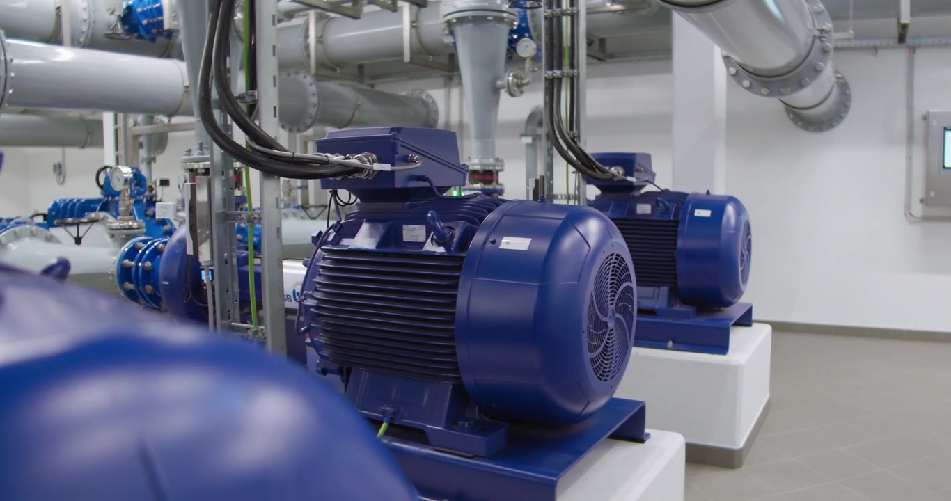 Pompe idrauliche industriali in funzione in una stazione di pompaggio, che spostano l'acqua attraverso tubi e valvole. Macchinari pesanti per l'approvvigionamento idrico, il trattamento delle acque reflue e i sistemi infrastrutturali