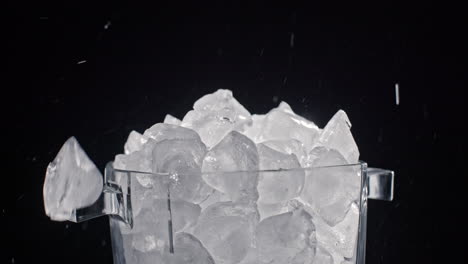 los cubos de hielo de una máquina de hielo se ponen en un recipiente de vidrio con hielo. vídeo en cámara lenta