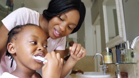 Mother-teaching-her-daughter-to-brush-her-teeth-in-bathroom-4k