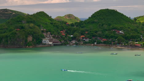 Turquoise-bay-with-lush-hills-and-village-in-lombok-gerupuk,-indonesia,-aerial-view