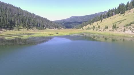 aerial - drone flies low above clear blue lake