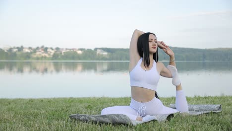 a young woman in sportswear stretches her legs in a city park a young woman in sportswear stretches her legs in a city park wellness summer fitnessyoung slim woman does relax exercises near lake