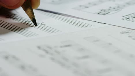 A musician composer writes, on the empty pentagram, the notes of his new song or opera. The musician composes his new music.