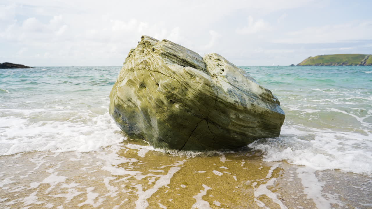 Large rock on a sandy beach with waves
