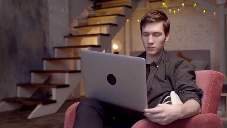 молодой человек работает на ноутбуке дома