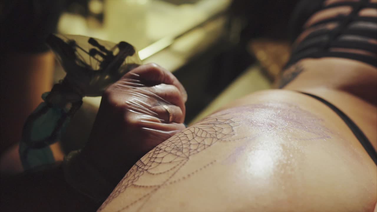 artista del tatuaje trabajando en un diseño de tela de araña tatuaje en la espalda de una mujer
