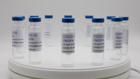 transparent empty glass vials with covid-19 vaccine label on rotating display