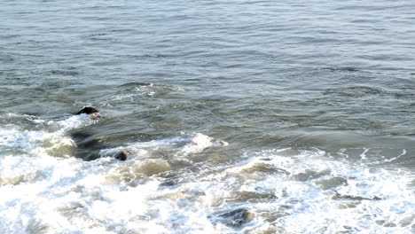 waves hitting the rocky shoreline of big rock beach malibu at golden magic hour time