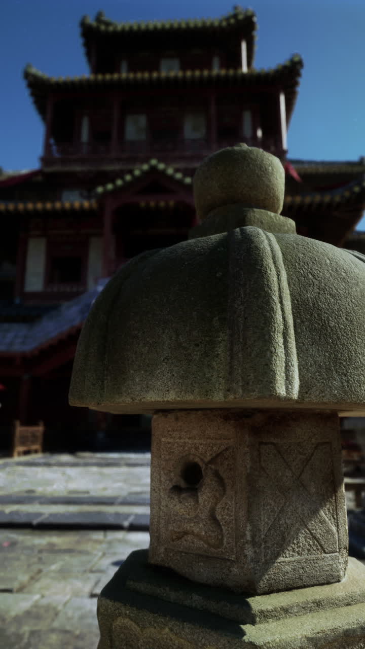 close up de una linterna de piedra frente a un templo tradicional chino