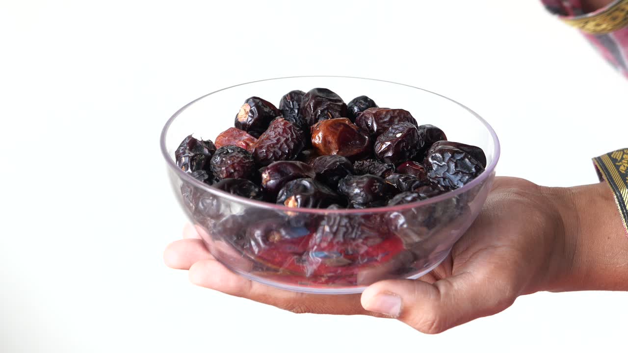 Hand holding a bowl of dates
