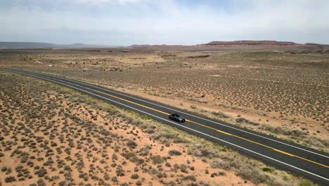 Eine-Luftdrohnenaufnahme-Eines-Ford-Mustang-Autos,-Das-Auf-Der-Autobahn-Der-Route-66-Fährt