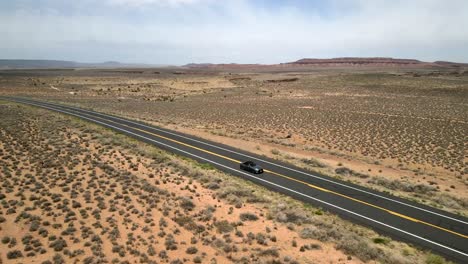 an aerial drone shot of a ford mustang car vehicle traveling on the highway of route 66