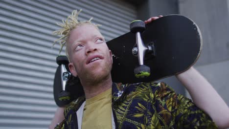 Happy-albino-african-american-man-with-dreadlocks-walking-and-holding-skateboard