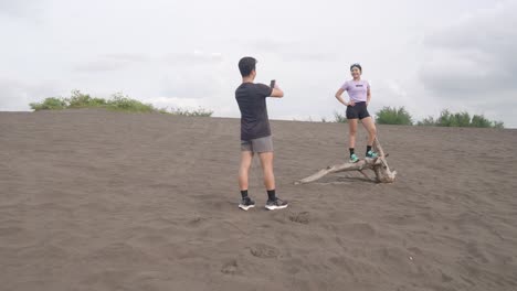 couple posing on driftwood in sand dune