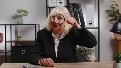 senior businesswoman looking through magnifying glass