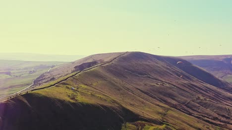 aerial sunset view of mam tor, peak district with paragliders soaring