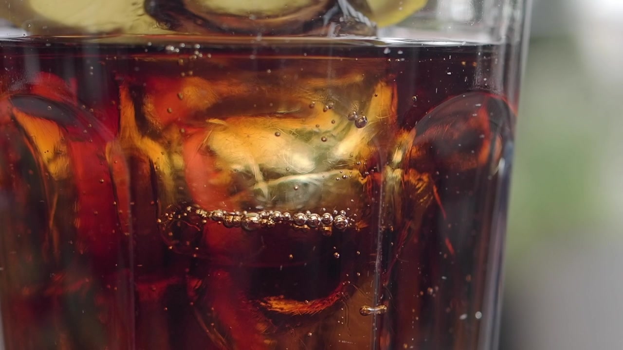Primo piano di cola rinfrescante con cubetti di ghiaccio e fette di limone