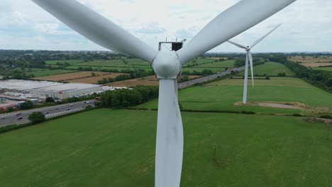 aerial drone cinematic footage of renewable wind energy turbines and industrial distribution centres near lutterworth england uk