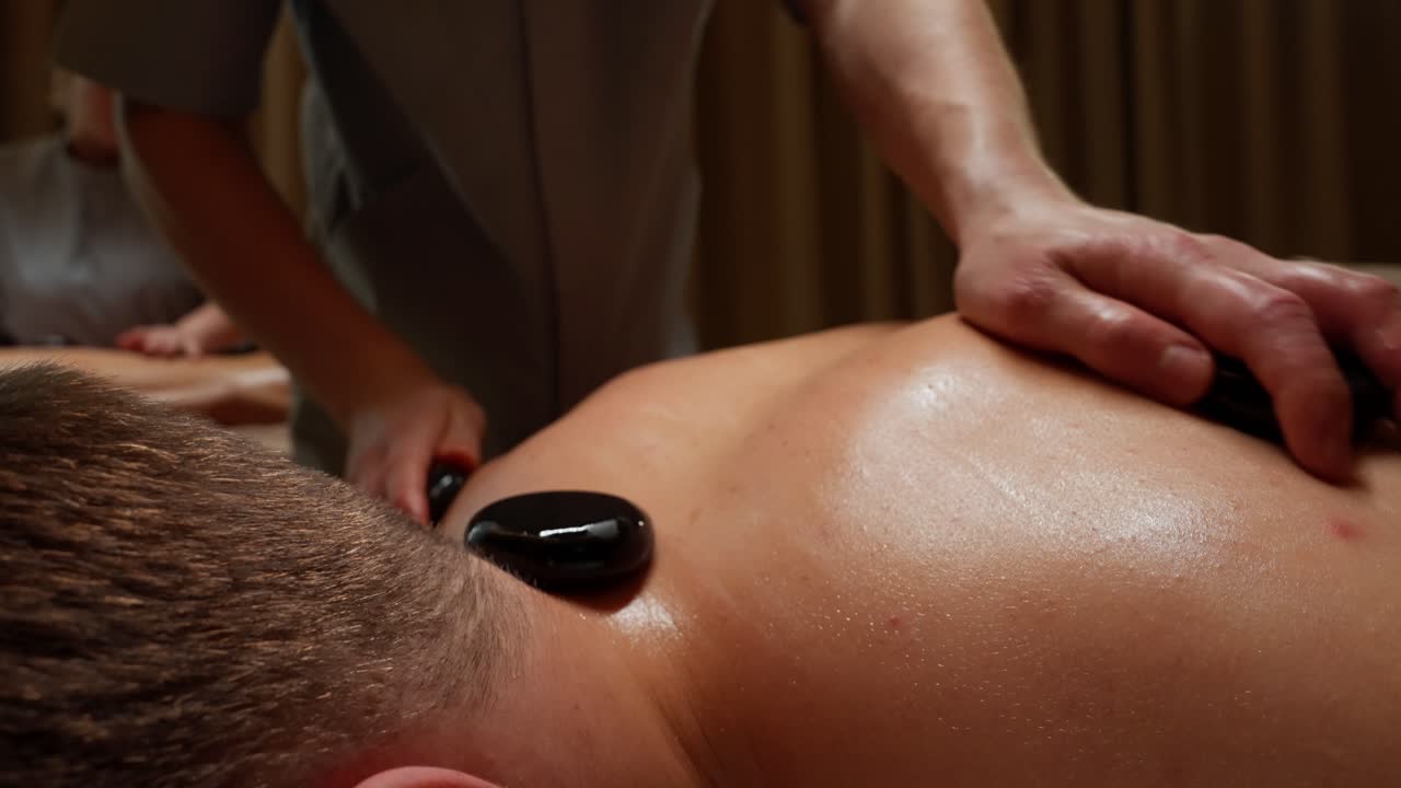 Terapeutisk hot stone-massage på en persons ryg