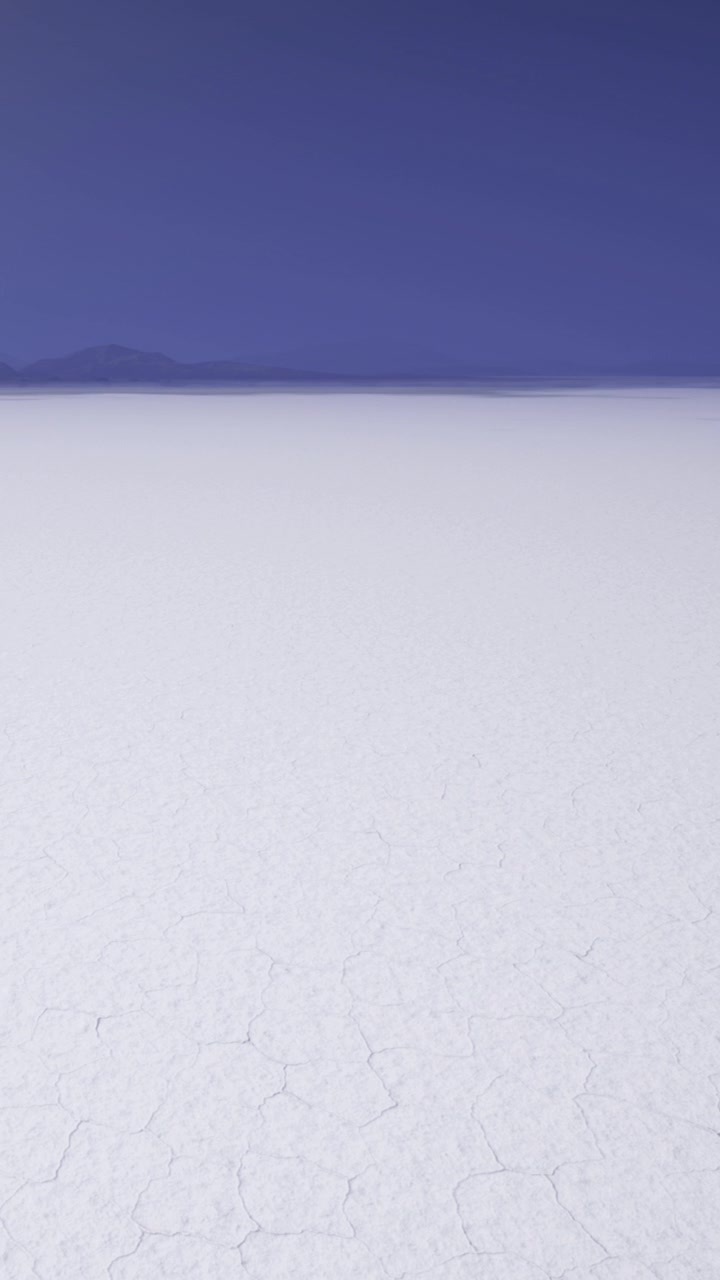Salar blanco se extiende bajo un cielo azul con montañas distantes en Bolivia.