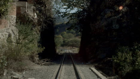 Point of view of a train moving over railroad tracks alongside the country and crossing a tunnel