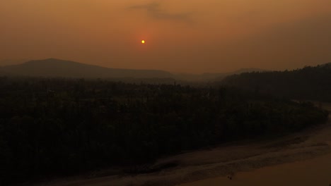 a warm sunset casts golden light behind the silhouettes of trees, creating a tranquil and scenic view of nature’s beauty at dusk in a quiet forest or countryside setting.