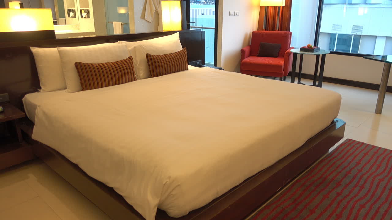 Large luxury hotel room decorated in warm red tones large windows looking to the outside